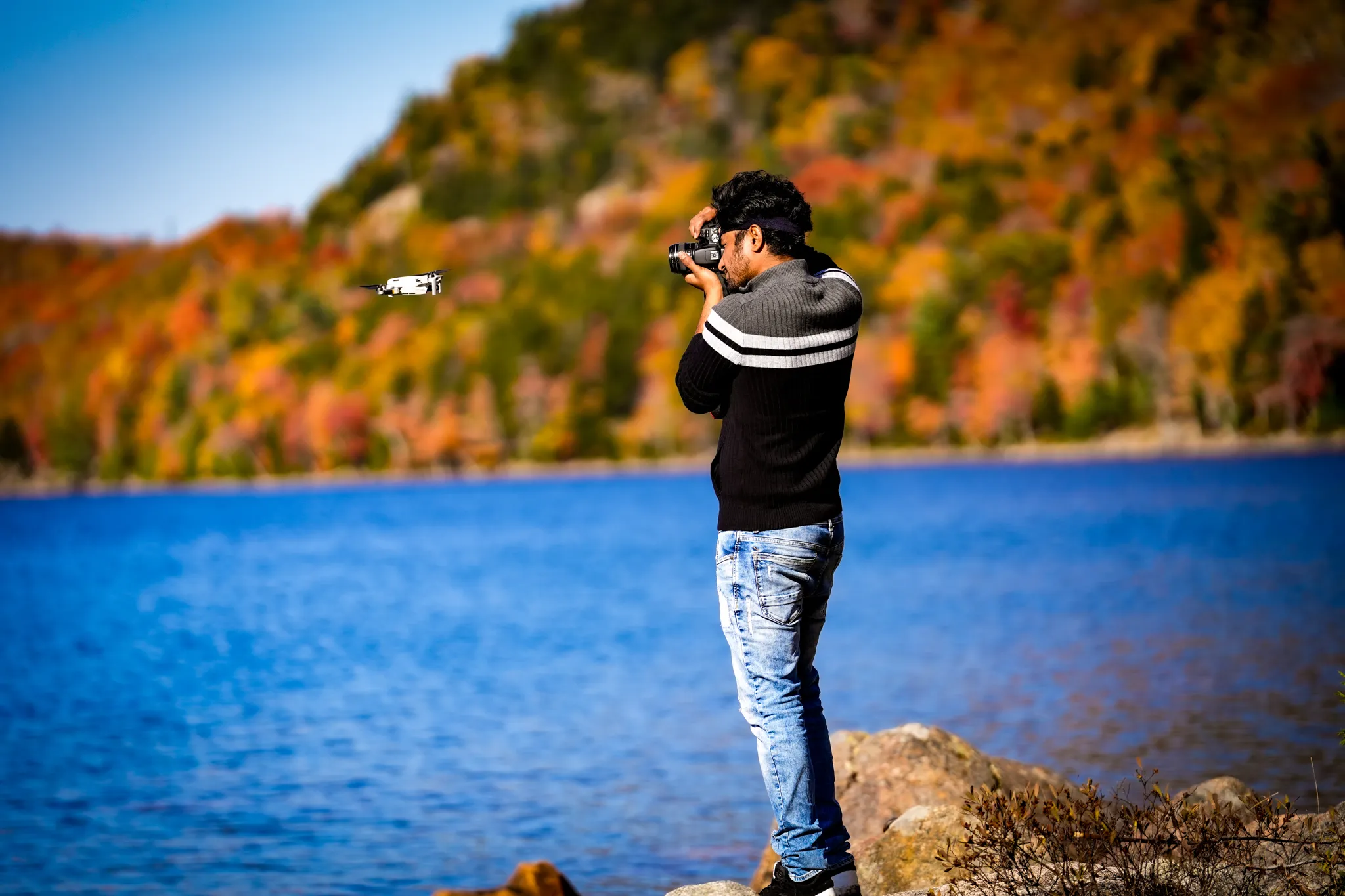 Photographer capturing a fall lakeside scene with a drone in flight — the Goldhour approach